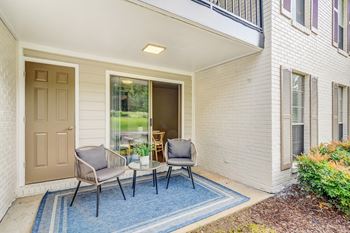 A patio with two chairs and a table on a blue rug